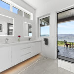 Bright and white, extraordinary bathroom with double- sink and lots of windows and lift and slide door.