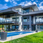 Under the striking blue sky stands the modern 2 story home with a outdoor swimming pool.