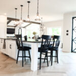 Next level white kitchen with black accents, chairs. Oversized sliding doors are also in black.
