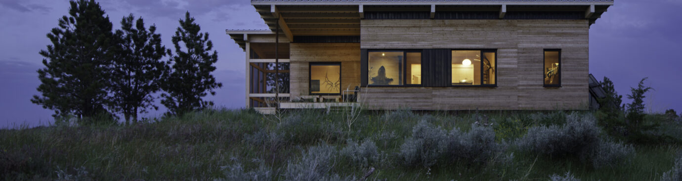 Hunting cabin perched up on a Hill in Montana's county site. The surrounding evening sky and the grass, brush and trees add to the astonishing beauty!