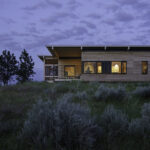 Hunting cabin perched up on a Hill in Montana's county site. The surrounding evening sky and the grass, brush and trees add to the astonishing beauty!