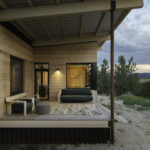 Rustic cabin porch, wooden plank exteriors. Also shows wood framed outside furniture.