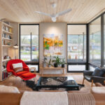 Modern design and quality are at the forefront of this inviting living room, surrounded by floor-to-ceiling windows and patio doors.