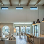 Modern prairie-style luxury home with oversized energy-efficient windows, black window frames, and an open- concept living space.